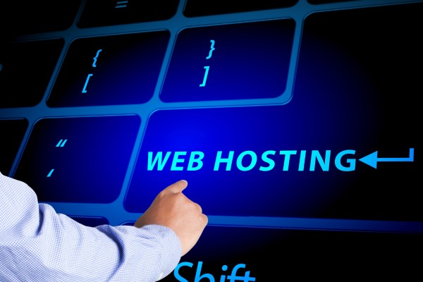 Person pointing at large keyboard with "Web Hosting" key highlighted.